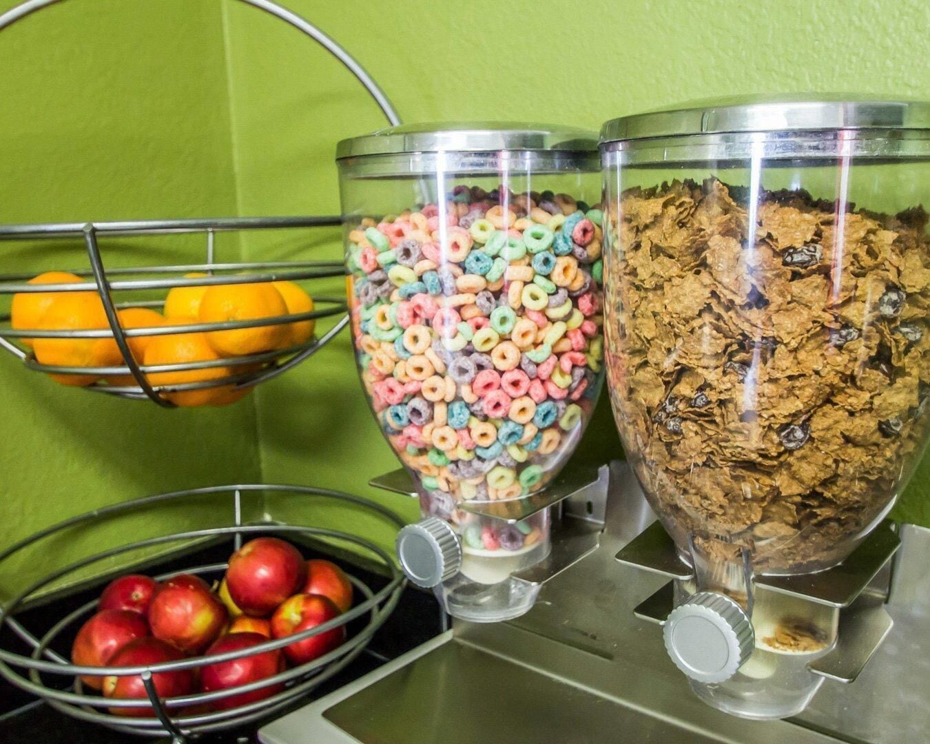 A food service area with metal bowls containing cereal and apples.
