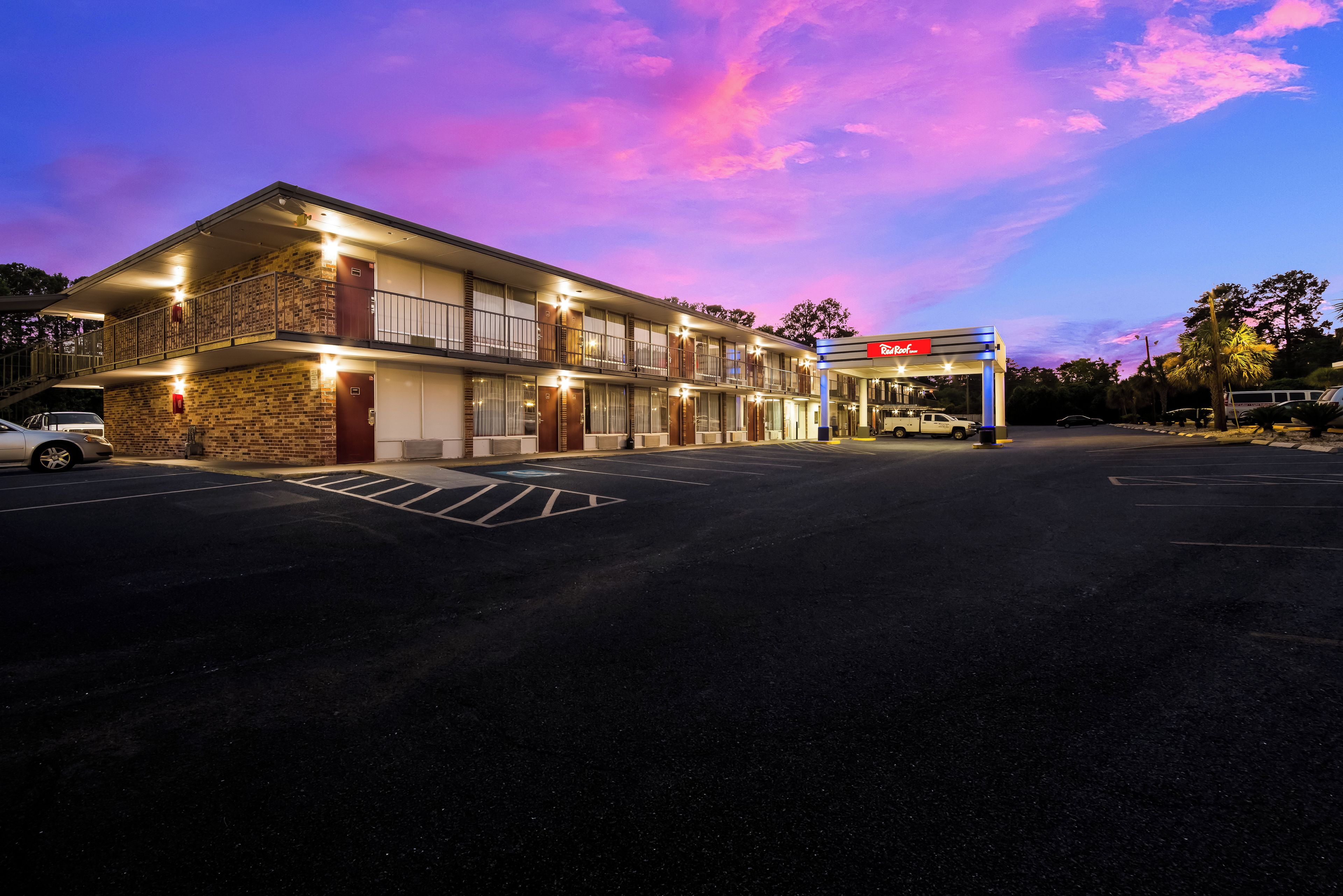 A motel with a gas station, multiple floors, and a parking lot.