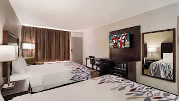 Een hotelkamer met twee bedden, een bureau, een televisie en een spiegel.