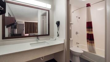 A bathroom with a white sink, a mirror, a hairdryer, a toilet, and a shower curtain.