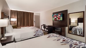 Une chambre d’hôtel avec deux lits, un bureau, une télévision et un miroir.