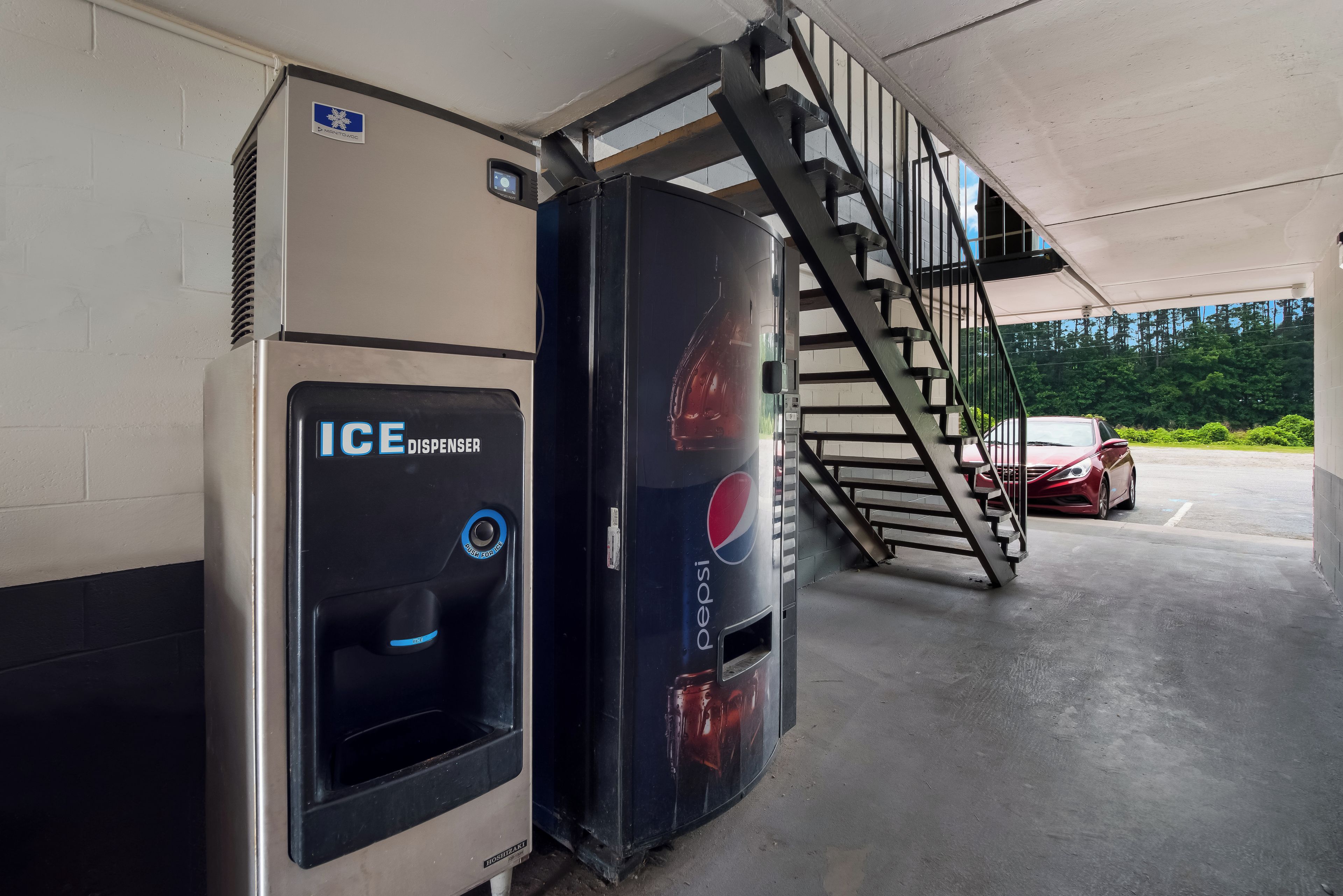 A parking garage with a Pepsi dispenser and an ICE dispenser.