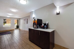 A modern kitchen area with a coffee machine, a refrigerator, and a window with blinds.
