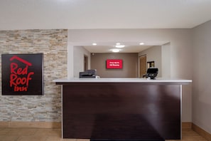 A reception desk with a flat-screen TV displaying 'Free Wi-Fi All Rooms' and a digital printer. - Red Roof Inn Columbia, SC Airport (West Columbia)