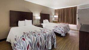 A hotel room with two beds, a nightstand, a lamp, a desk, and a door. - Red Roof Inn Columbia, SC Airport (West Columbia)