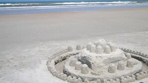A sandy beach with a circular sandcastle structure.