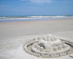 Una playa arenosa con una estructura de castillo de arena circular.