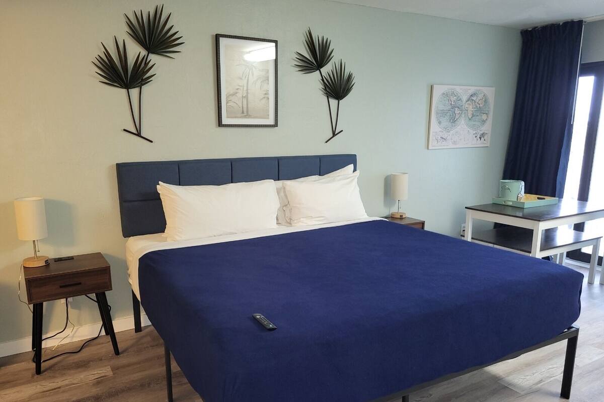 A neatly arranged hotel room with a large bed, a desk, and a chair.