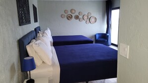 A bedroom with two beds, a nightstand, a lamp, a chair, and decorative wall art.