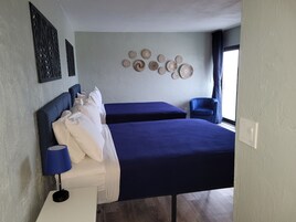 Un dormitorio con dos camas, una mesita de noche, una lámpara, una silla y decoración en la pared.