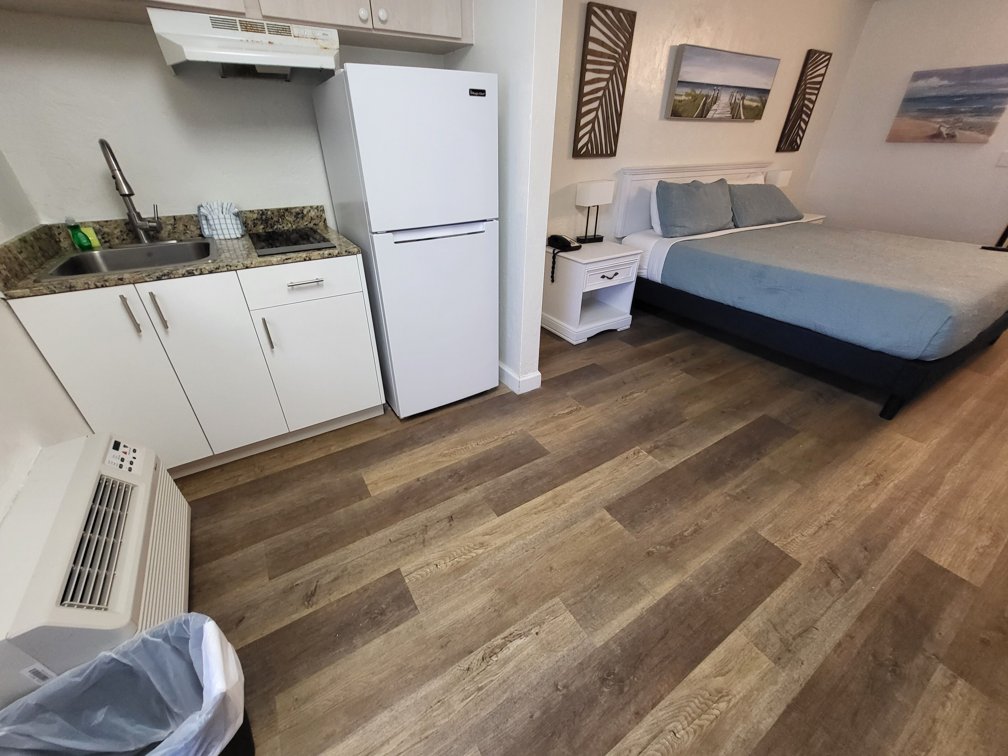 Habitació compacta amb cuina americana, un llit i una petita taula de nit.