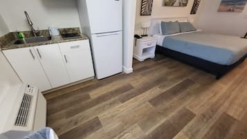 Habitació compacta amb cuina americana, un llit i una petita taula de nit.