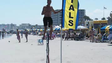 Eine Person fährt auf einem Einrad über einen sandigen Strand, mit einer Flagge mit dem Aufdruck 'PINTALS'.