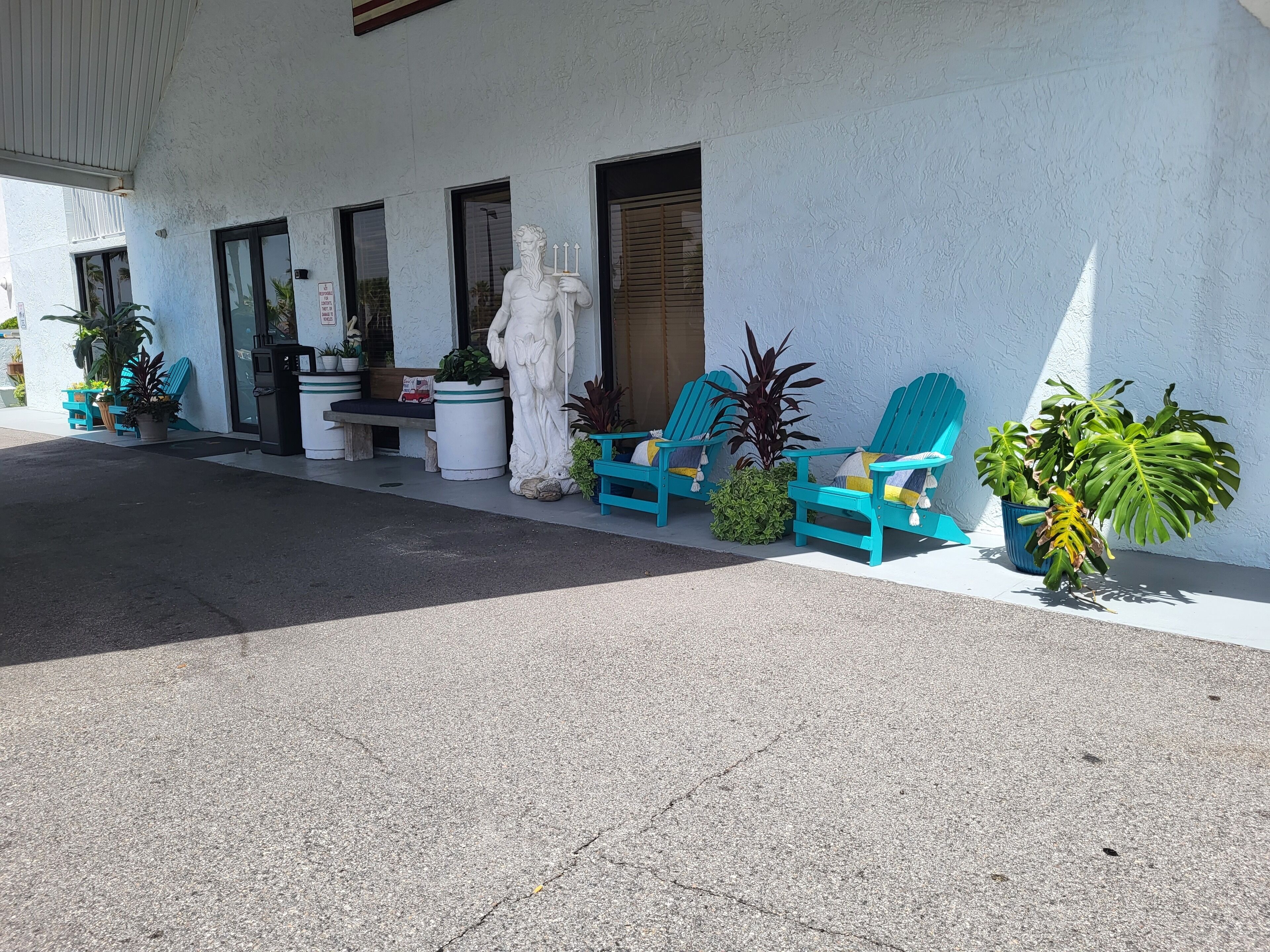 Un edificio de fachada blanca, una estatua y varias plantas en macetas.