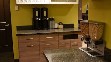 Eine Küche mit einer Granitabdeckung, eingebauten Schränken, einer Kaffeemaschine und einem Glas auf der Arbeitsfläche.