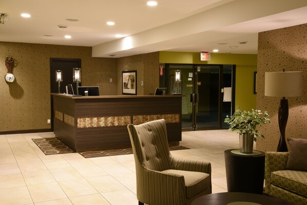 A reception area with a reception desk, a chair, a small table with a plant, and a wall clock.
