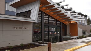 L’extérieur de l’hôtel Pacific Inn présente un design moderne, avec une entrée abritée et un espace de stationnement bien visible.