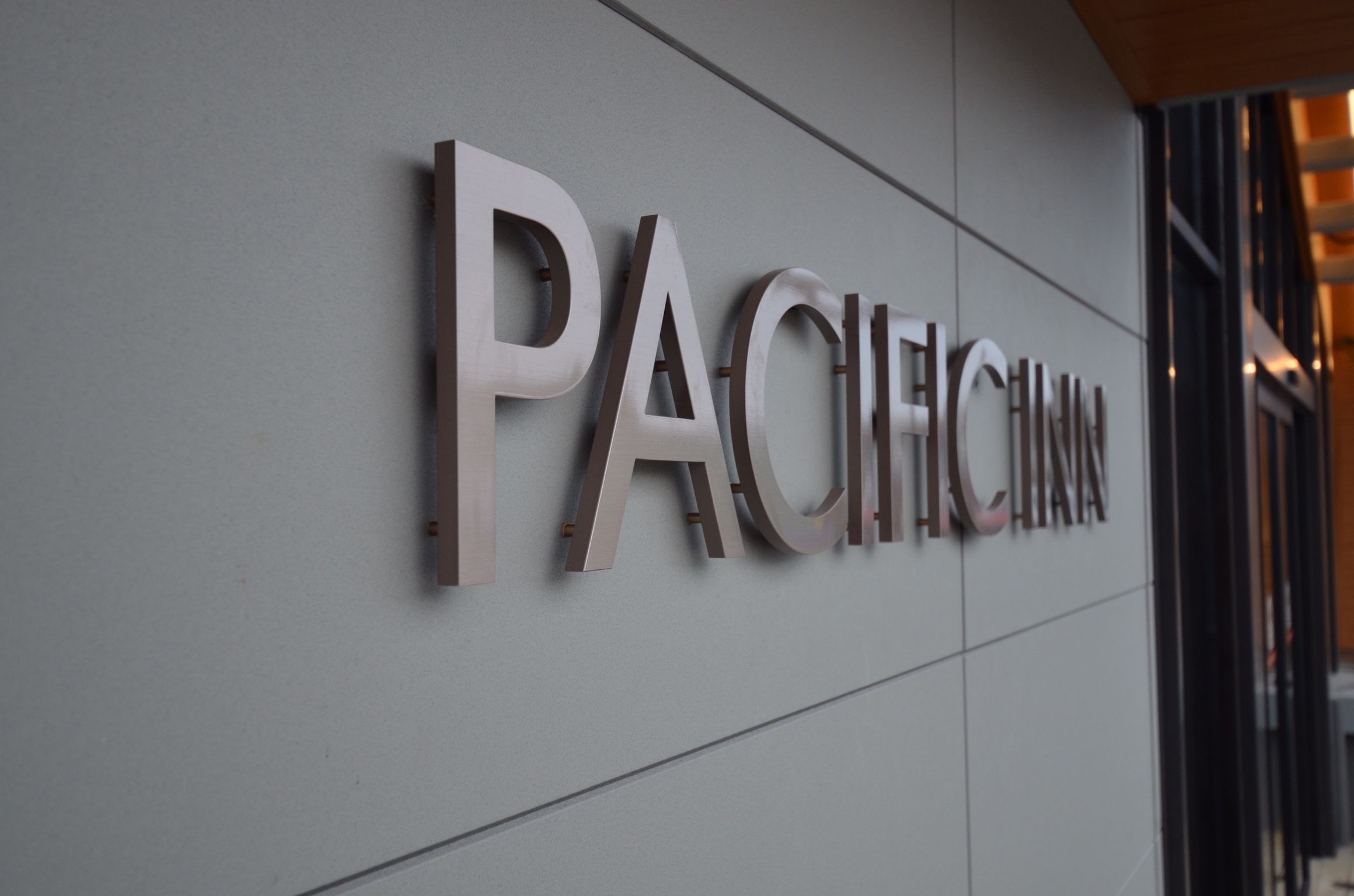 A metallic sign with the word "PACIFIC" on a building facade.