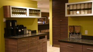 Une cuisine moderne dotée d’appareils électroménagers intégrés, de meubles en bois et d’un espace dédié à la préparation du café.
