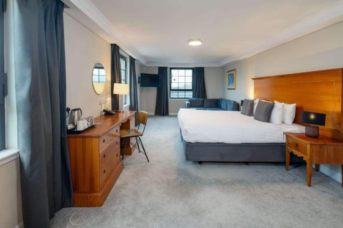 A hotel room with a large bed, a desk with a chair, a dresser, and a TV.