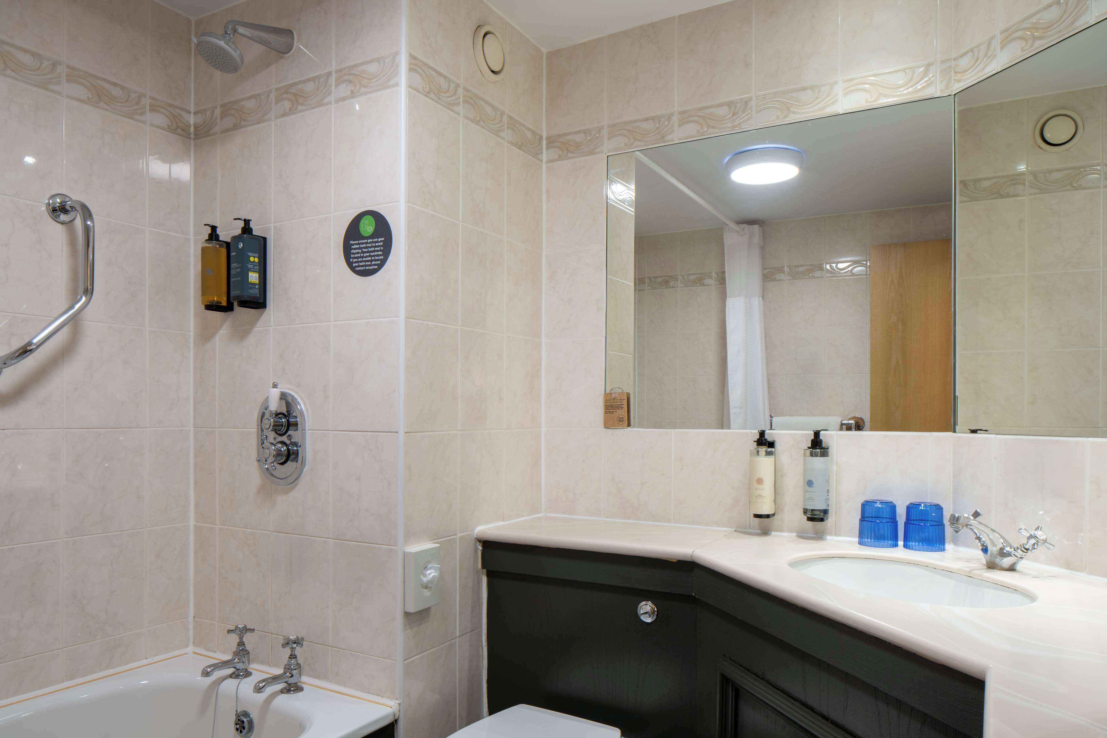 Een badkamer met een bad, een wastafel, een spiegel en een douche.