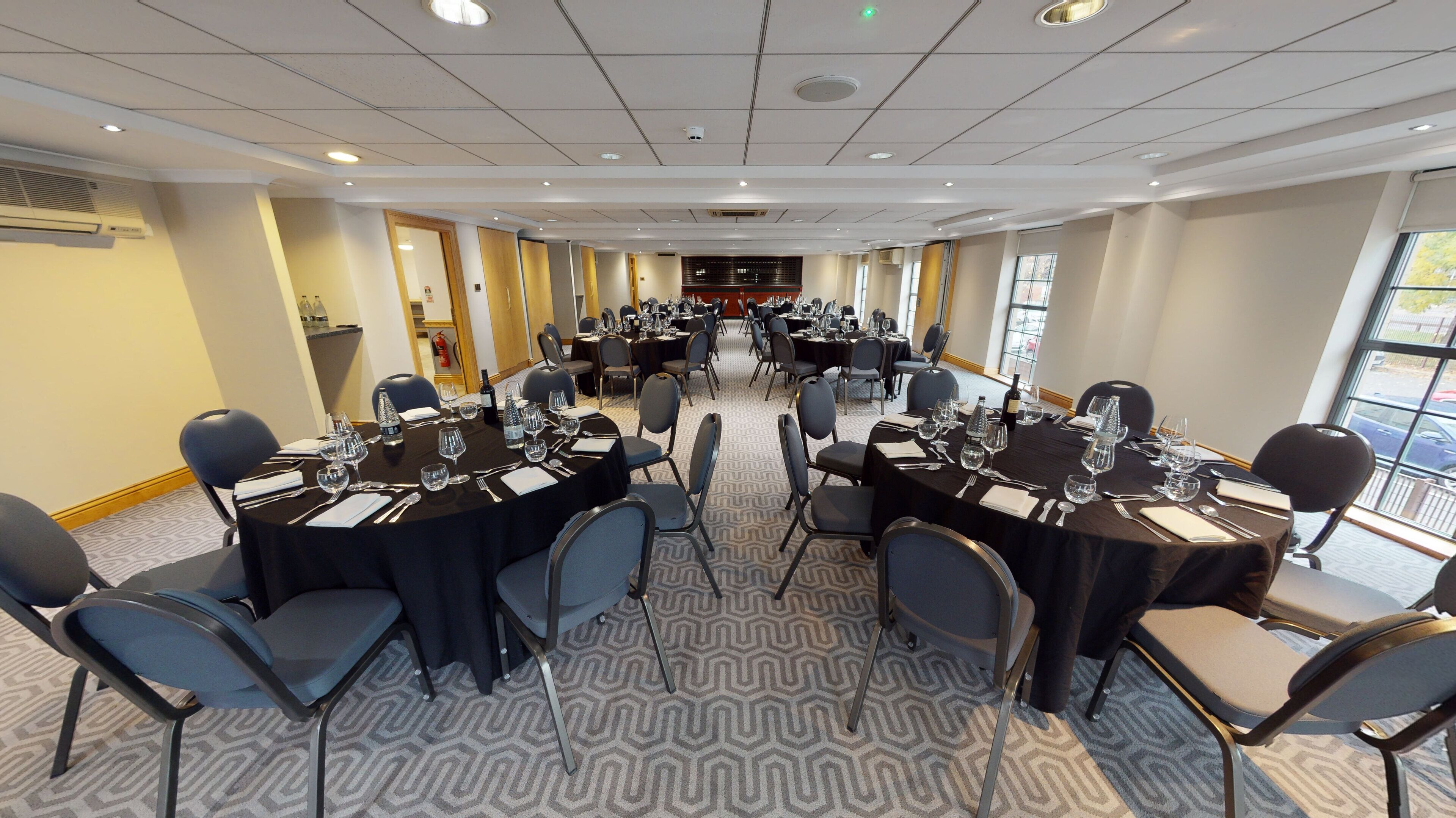 A conference room with multiple tables set for dining, equipped with chairs and dining essentials.