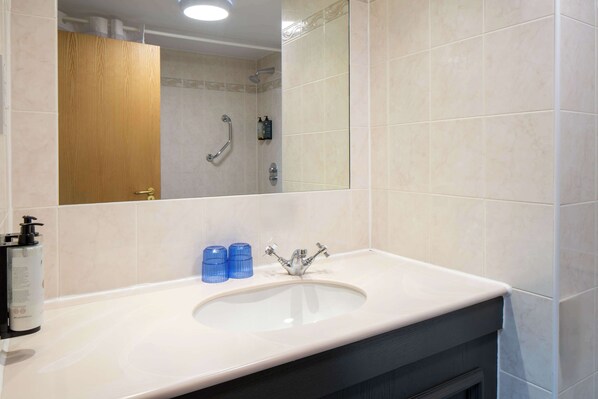 A bathroom with a white sink, a mirror, and a shower.