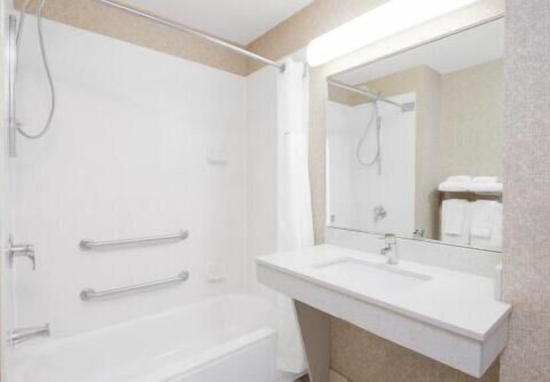A modern bathroom with a bathtub, a sink, and a large mirror.