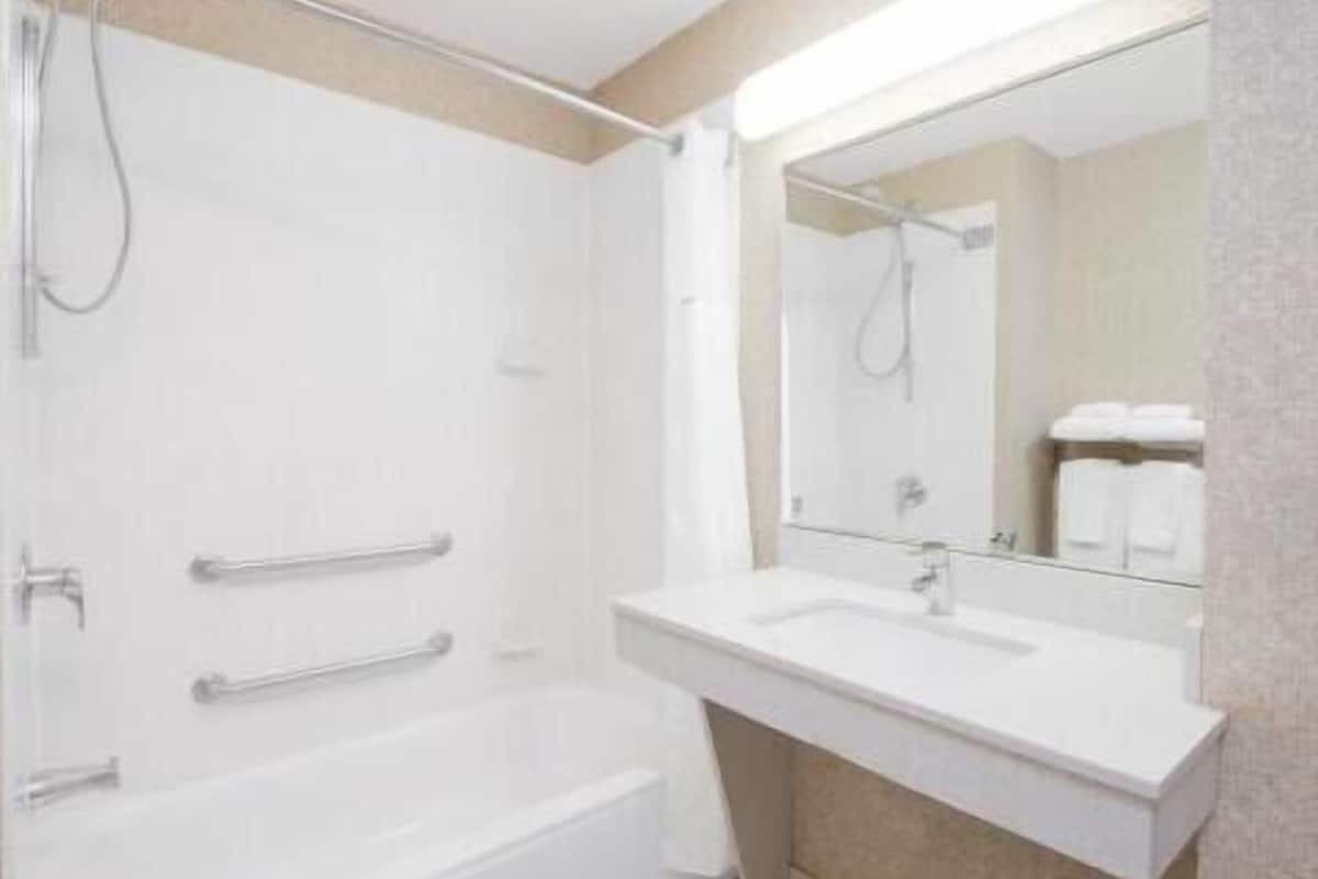 A modern bathroom with a bathtub, a sink, and a large mirror.
