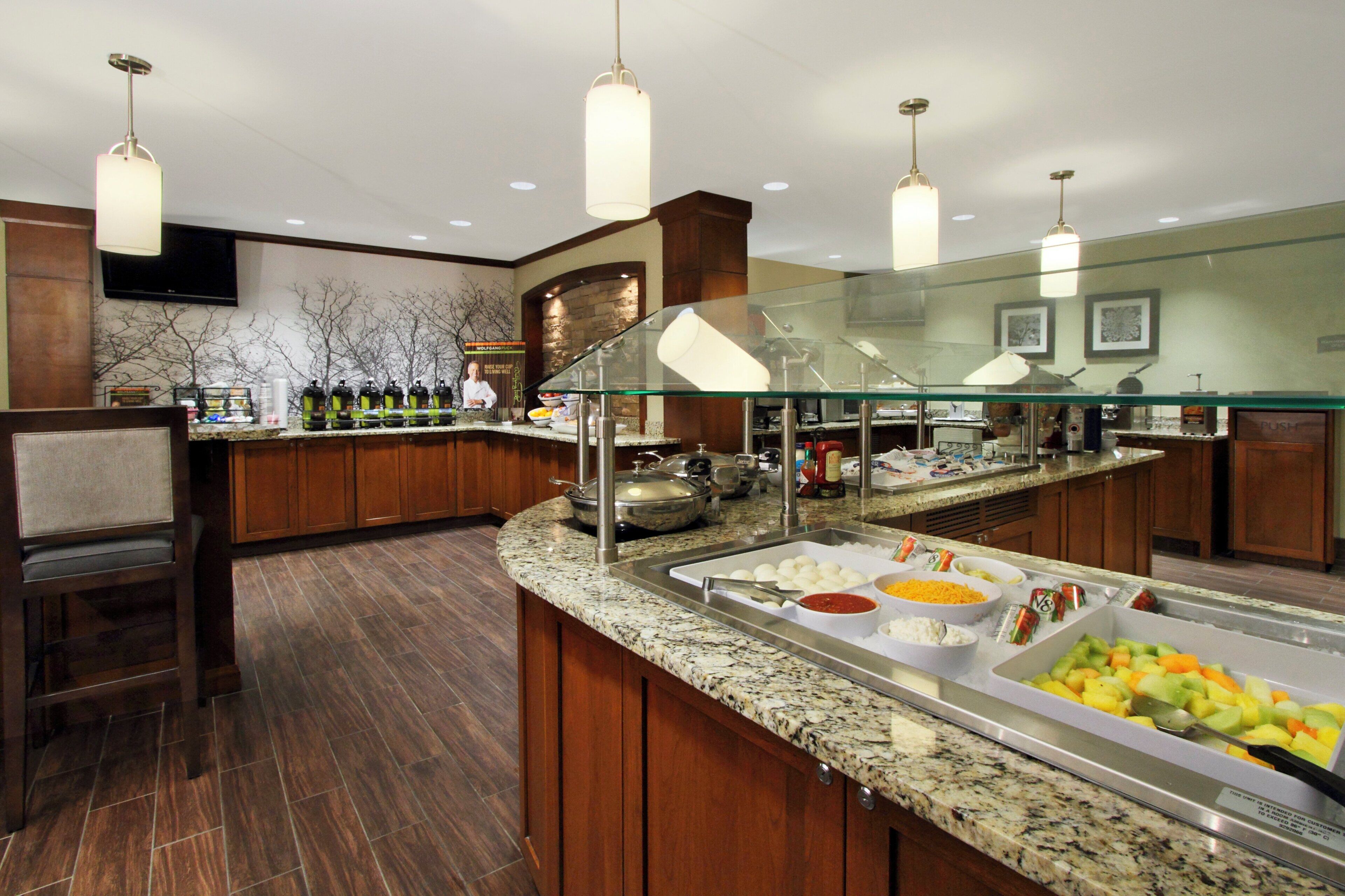 A buffet area with a variety of food options, including fruits and a salad bar, in a hotel setting.