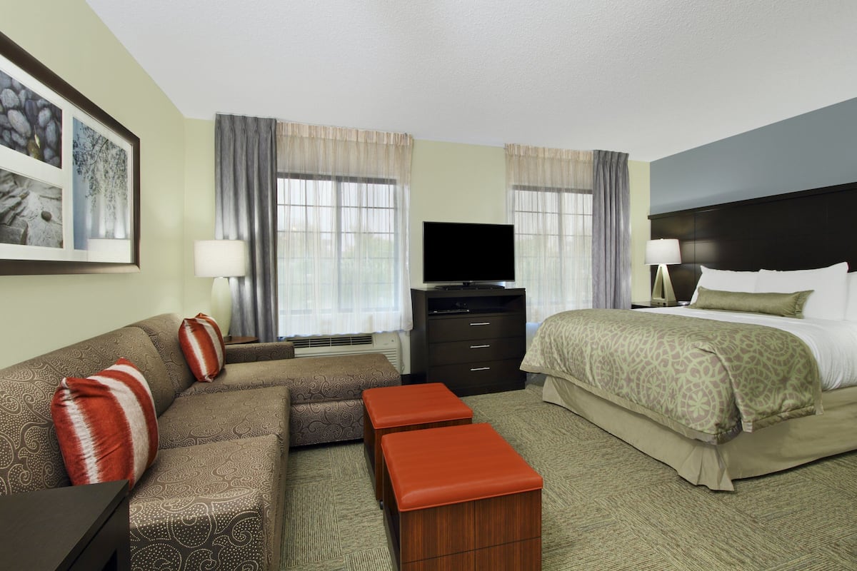 A hotel room with a bed, a sofa, a TV, and a desk.
