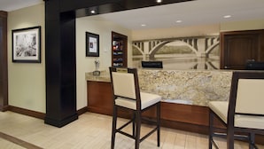 A bar area with two bar stools, a granite countertop, and a framed picture on the wall. - Staybridge Suites Tysons - McLean by IHG (McLean)