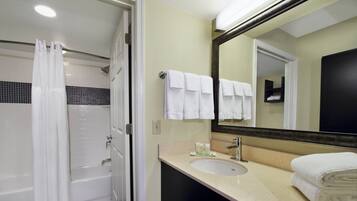 Un baño con bañera, lavamanos, espejo y toallas.