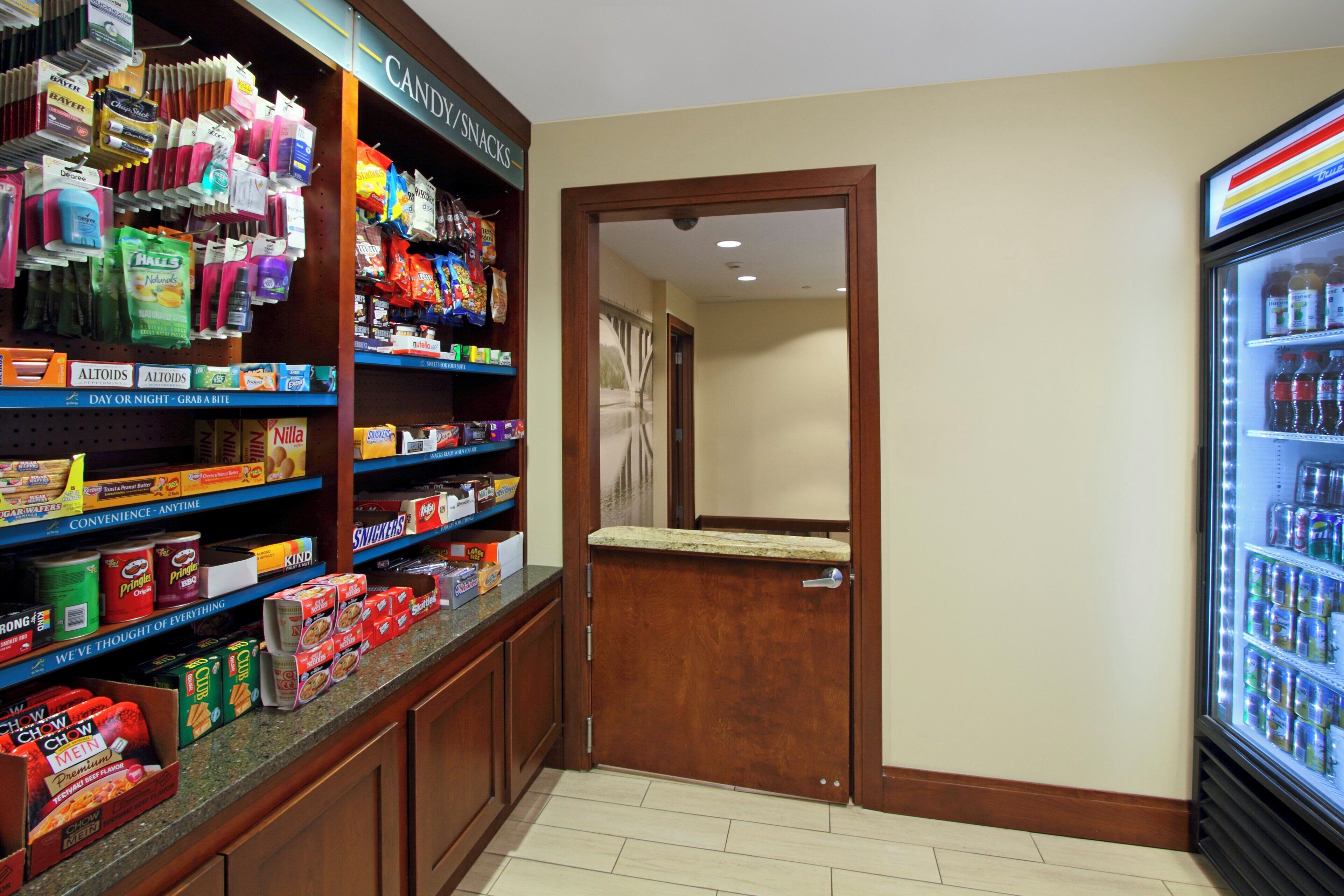 A snack and beverage section with various products on shelves and a refrigerator.