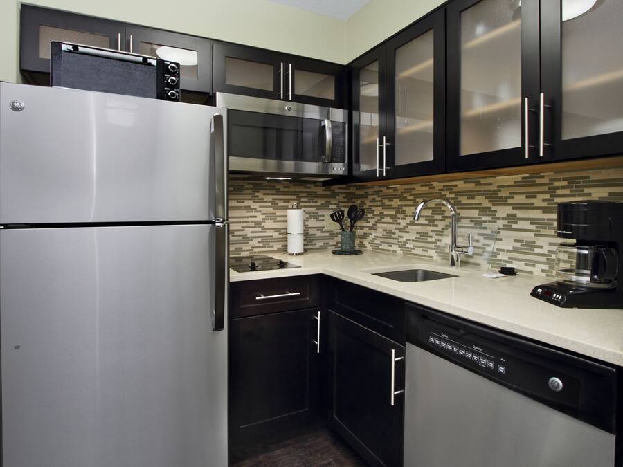 Una cocina moderna con refrigerador de acero inoxidable, microondas, cafetera y lavavajillas.