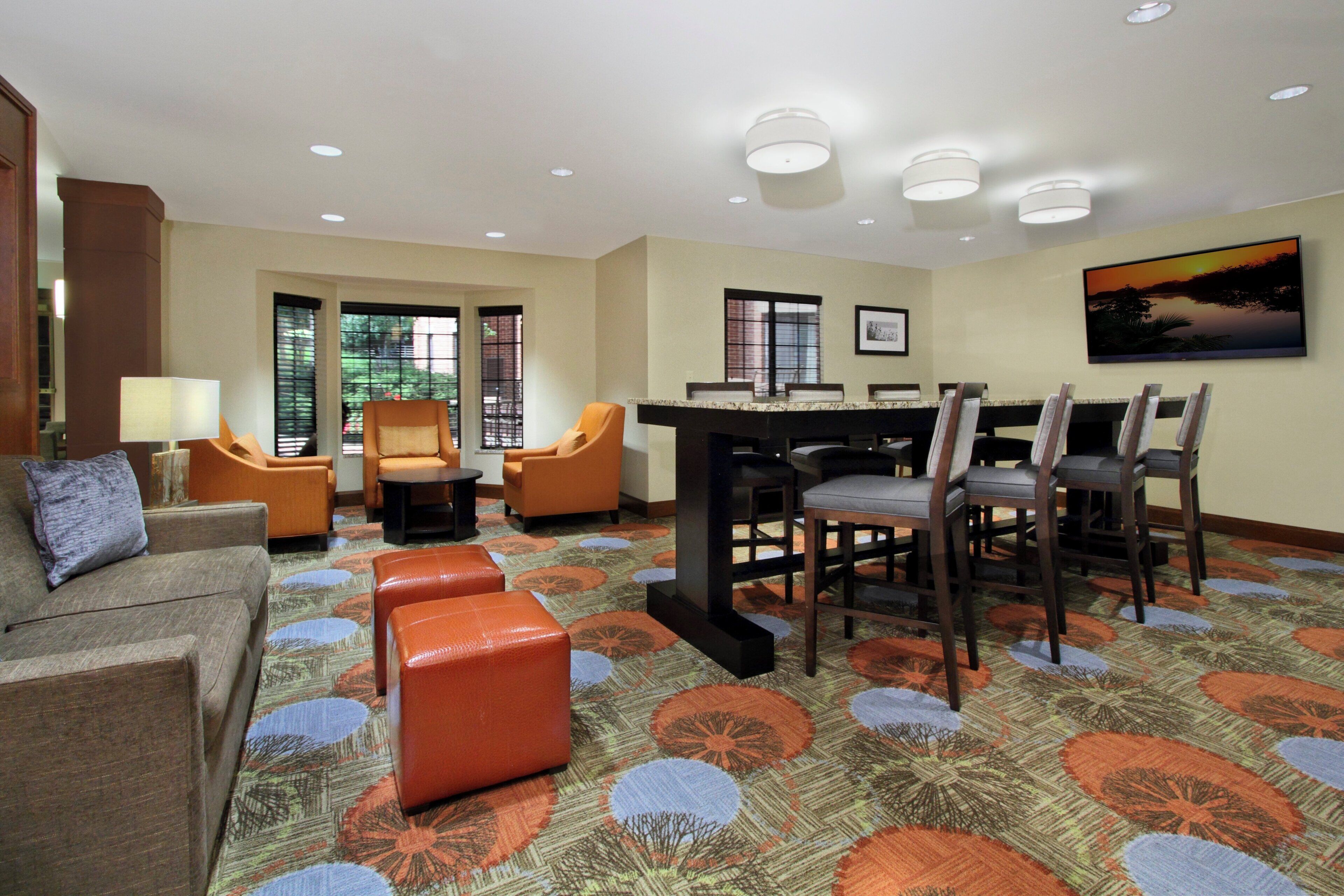 A hotel room with a dining area, a sofa, and a TV on the wall.