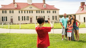 A family in front of a historic building with a red roof and white walls. - Staybridge Suites Tysons - McLean by IHG (McLean)