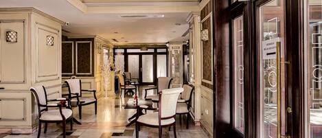 A hotel lobby with a marble floor, multiple dining tables, and chairs.