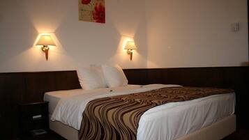 Una habitación de hotel con una cama grande, dos lámparas de pared y un cuadro en la pared.