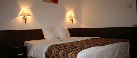 Una habitación de hotel con una cama grande, dos lámparas de pared y un cuadro en la pared.