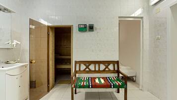 A bathroom with a bench, a toilet, and a shower area.