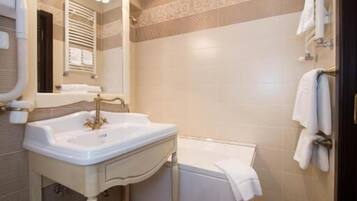 A bathroom with a sink, mirror, towel rack, and a shower area.