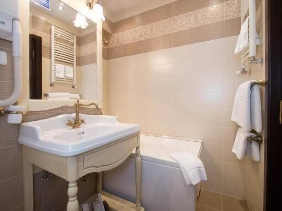 A bathroom with a sink, mirror, towel rack, and a shower area.