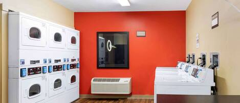 Un lavadero con varias lavadoras, un secador de pared y un sistema de ventilación.