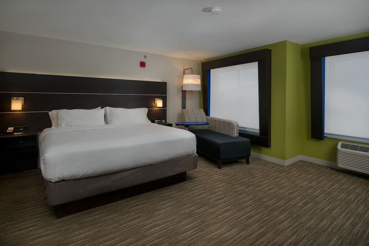 Una habitación de hotel con una cama grande, mesitas de noche, un escritorio, una silla y una ventana.