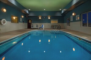 An indoor swimming pool with clear water, a lifeguard chair, and a no diving sign.