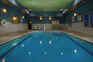 Piscina interna com água cristalina, cadeira de salva-vidas e placa de proibição de mergulho.
