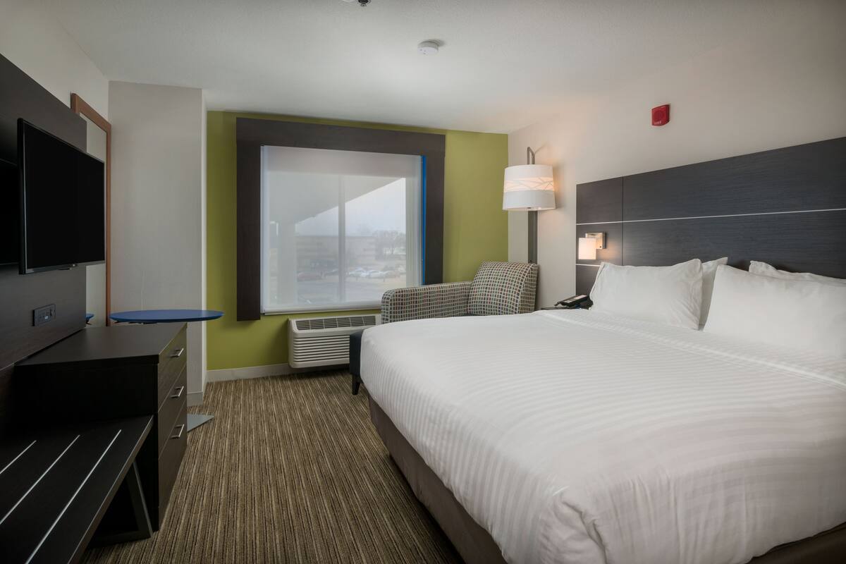 Habitación de hotel con una cama grande, un escritorio con televisor de pantalla plana, una silla, una ventana con vistas y una mesita de noche con lámpara.