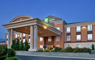 Edificio de Holiday Inn Express & Suites con entrada cubierta, varias ventanas y un área frontal ajardinada.
