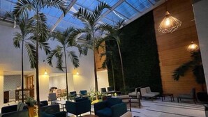 An indoor space with a high ceiling, palm trees, and modern seating. - DoubleTree by Hilton Hotel Veracruz (Veracruz)